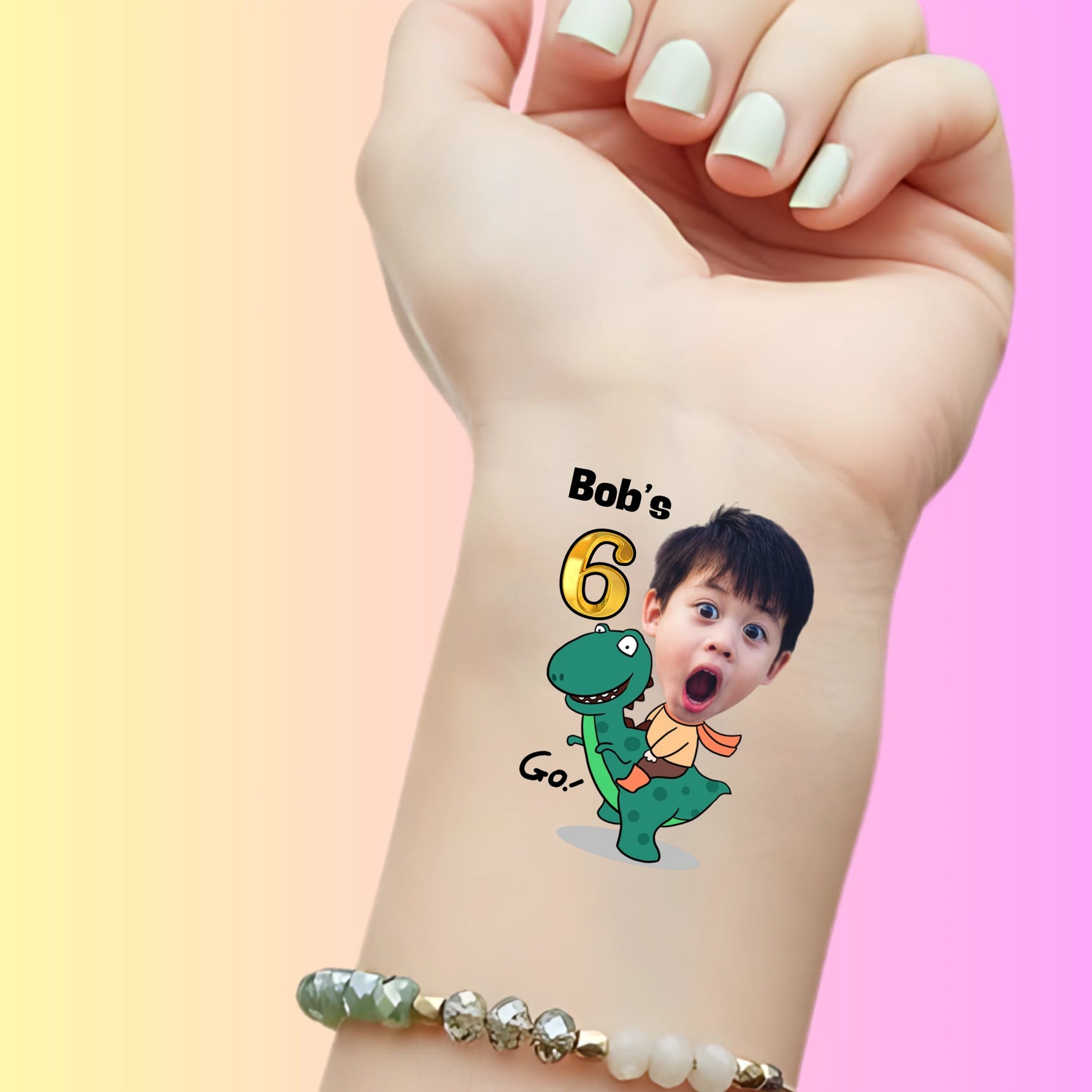 Custom temporary tattoo on wrist featuring boy riding green dinosaur with text Bob's 6 Go! for birthday party favor