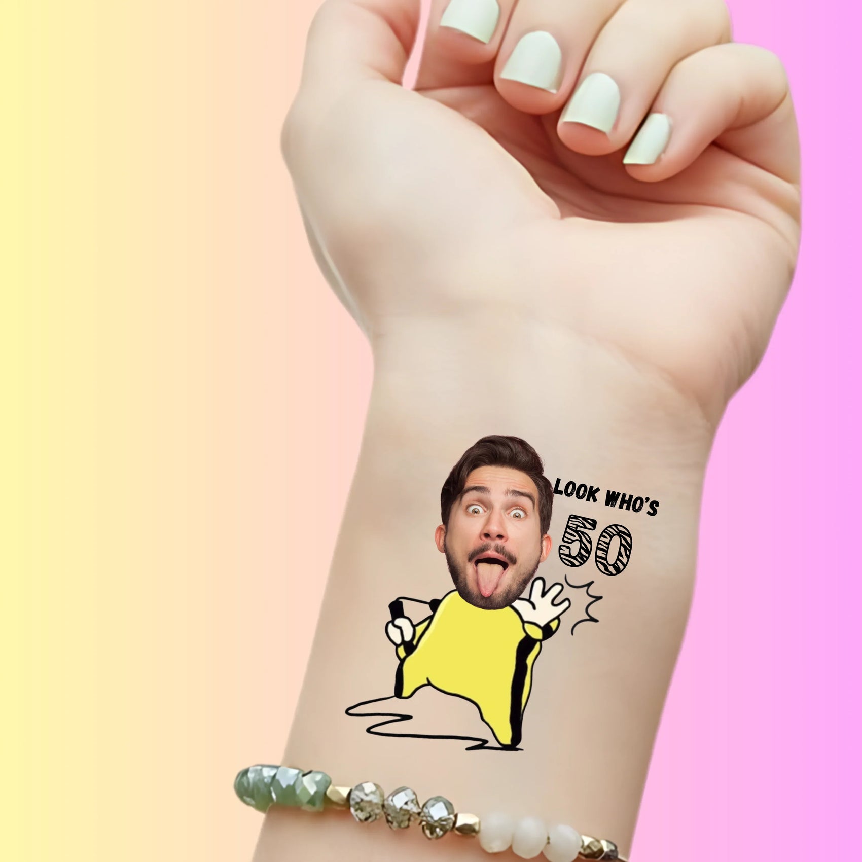 Custom temporary tattoo on wrist with cartoon body, funny male face, and text 'Look who's 50' for birthday favor