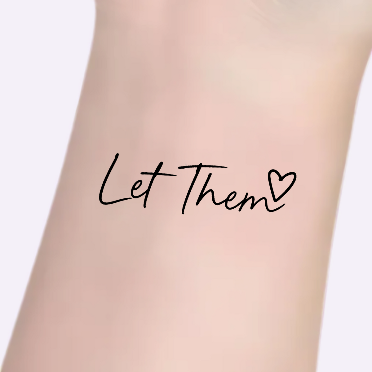 Let Them temporary tattoo in a close-up arm view, on a Whisper Lavender background.